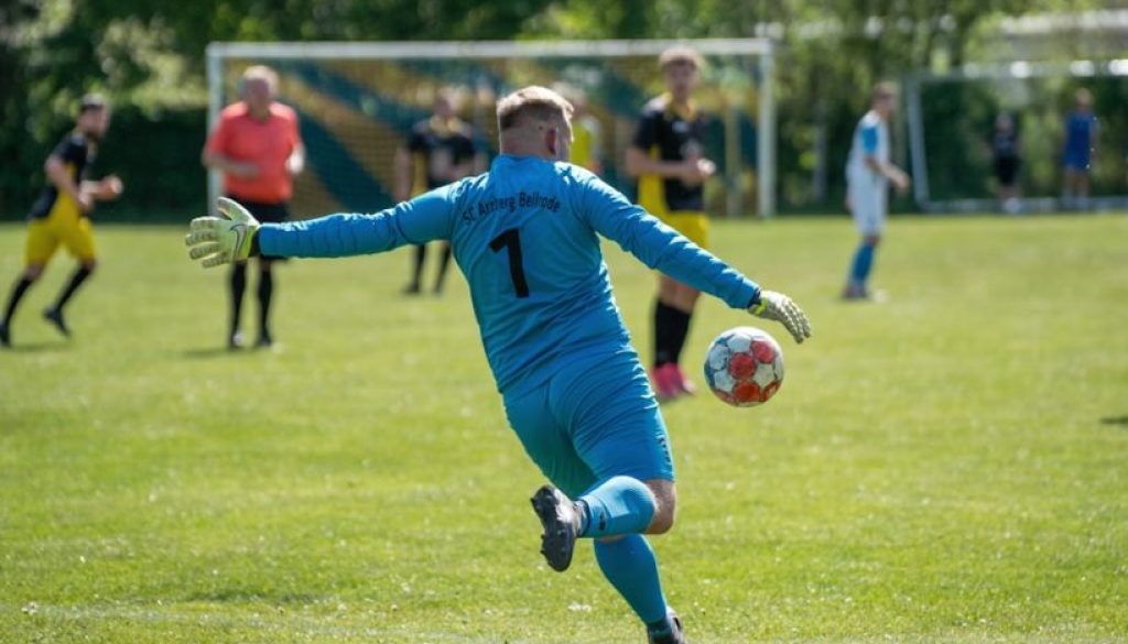 A goalkeeper kicks the ball during a soccer match.