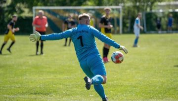 A goalkeeper kicks the ball during a soccer match.
